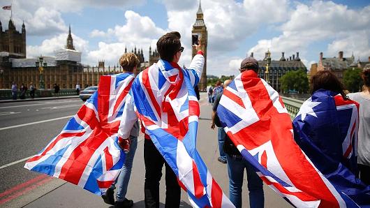 People walk over Westminster Bridge wrapped in Union flags towards the Queen Elizabeth Tower and The Houses of Parliament in central London