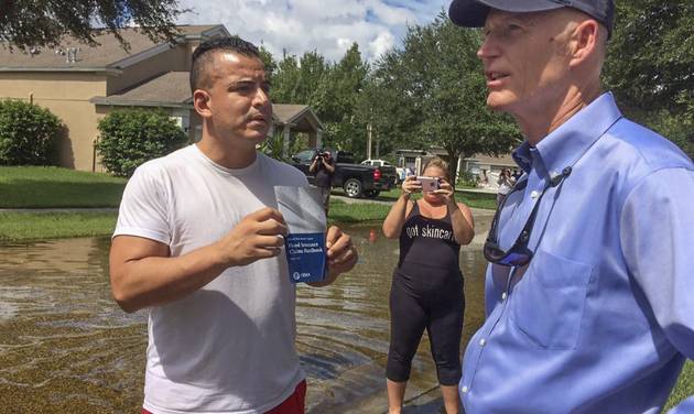 Robert Prescott 43 holds up a flood insurance book to show Florida Gov. Rick Scott in Pasco County Fla. Sunday Sept. 4 2016. Gov. Scott planned to meet with Pasco County officials to talk about the aftermath of Hurricane Hermine and the potential