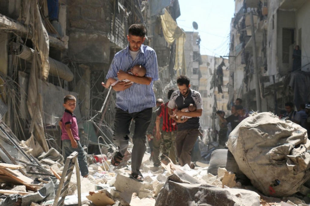 Syrian men carrying babies make their way through rubble after a reported air strike on the rebel-held Salihin neighbourhood of Aleppo Sunday