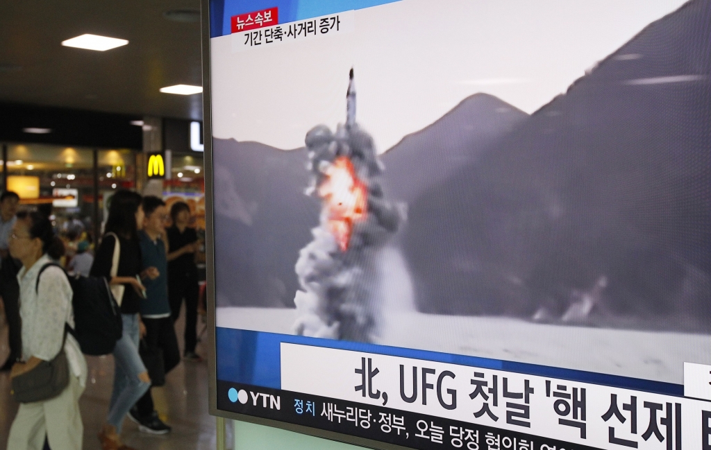 People pass by a TV news program showing a file footage of North Korea's ballistic missile that the North claimed to have launched from underwater at Seoul Railway station in Seoul South Korea Wednesday Aug. 24 2016. North Korea on Wednesday fir