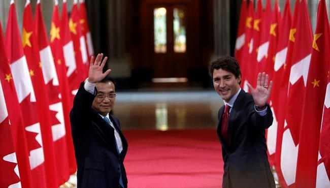 Chinese Premier Li Keqiang and Canadian Prime Minister Justin Trudeau wave after taking part in a signing ceremony on Parliament Hill in Ottawa on Thursday