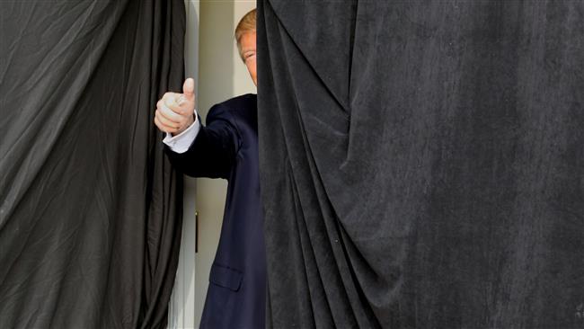 Republican presidential candidate Donald Trump gives a thumbs up from behind the curtain before taking the stage at an event