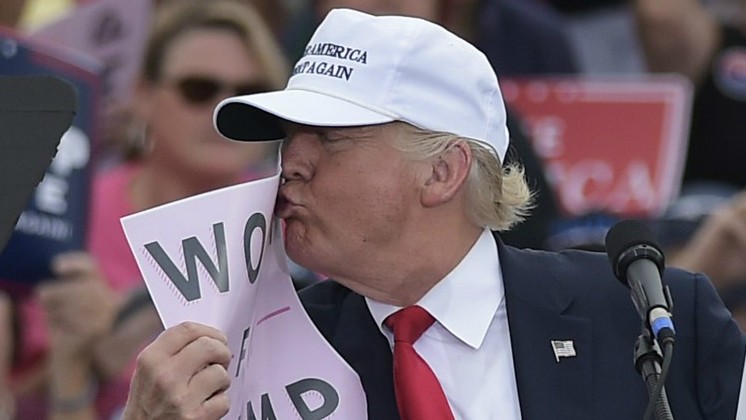 Republican presidential nominee Donald Trump kisses a'Women for Trump placard during a rally at the Lakeland Linder Regional Airport in Lakeland Florida