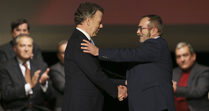 Colombia's President Juan Manuel Santos left shakes hands with with Rodrigo Londono known as Timochenko the top leader of the Revolutionary Armed Forces of Colombia FARC after signing a revised peace pact at Colon Theater in Bogota Colombia Thursd