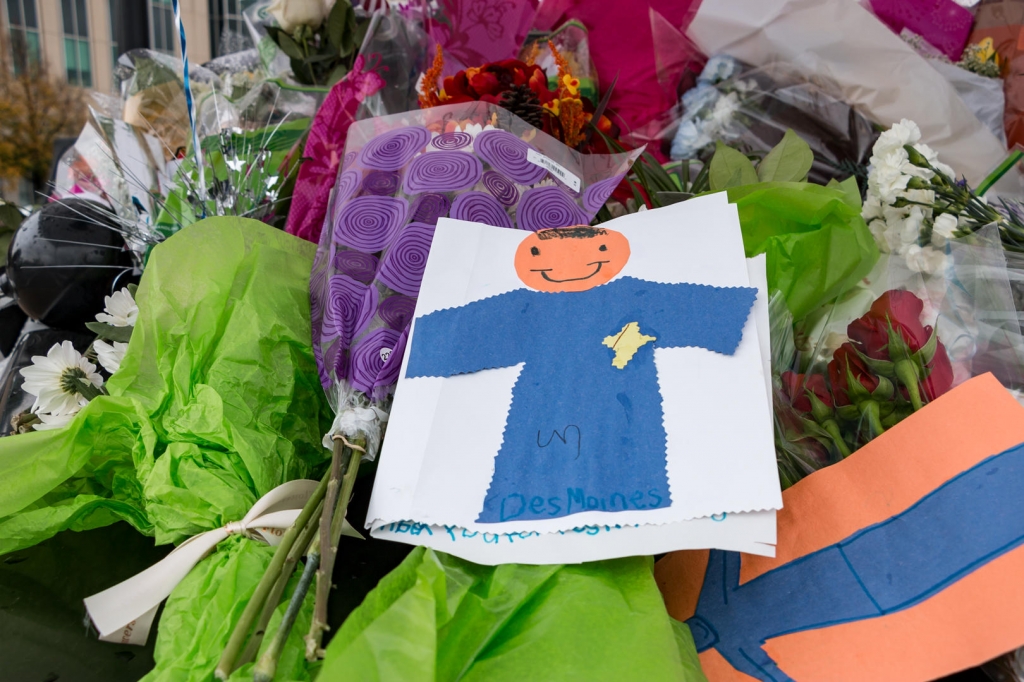 Flowers and handmade cards cover a police car parked outside of the Des Moines Police Department in memory of two officers killed in the line of duty