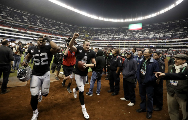 Oakland Raiders quarterback Derek Carr center reacts with teammate defensive end Khalil Mack after an NFL football game against the Houston Texans Mon