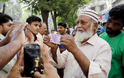 MUMBAI An Indian displays a new Rupees 2,000 currency note outside a bank in Mumbai yesterday. — AP