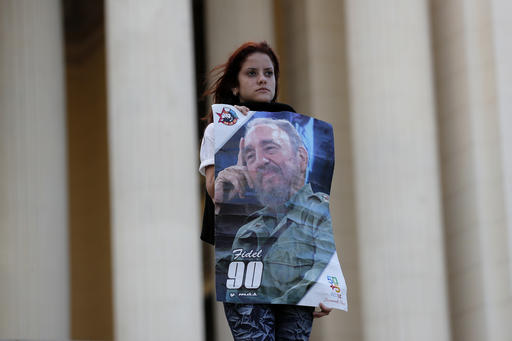 A student stands at attention holding images of Fidel Castro at the university where Castro studied law as a young man during a vigil in Havana Cuba Sunday Nov. 27 2016