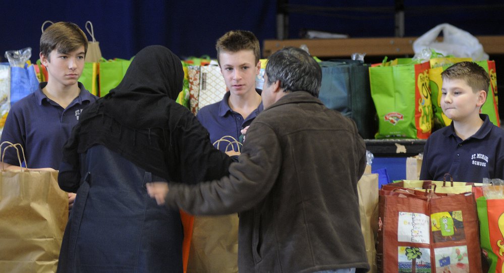 St. Michael eighth-graders help people collect bags of groceries Monday for the Thanksgiving holiday at the private Catholic school in Augusta. Several people collected the donated meals assembled by the students