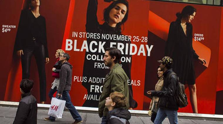 Shoppers pass by a retail store as they walk along Fifth Avenue on Black Friday in New York