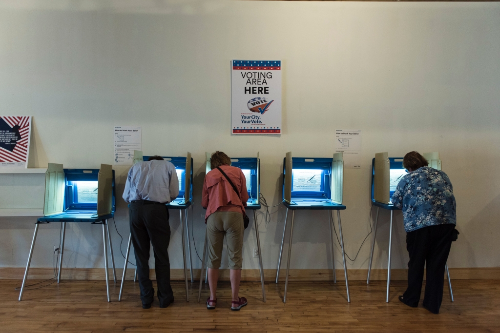 Three people vote in booths at the Early Vote Center in northeast Minneapolis Minnesota