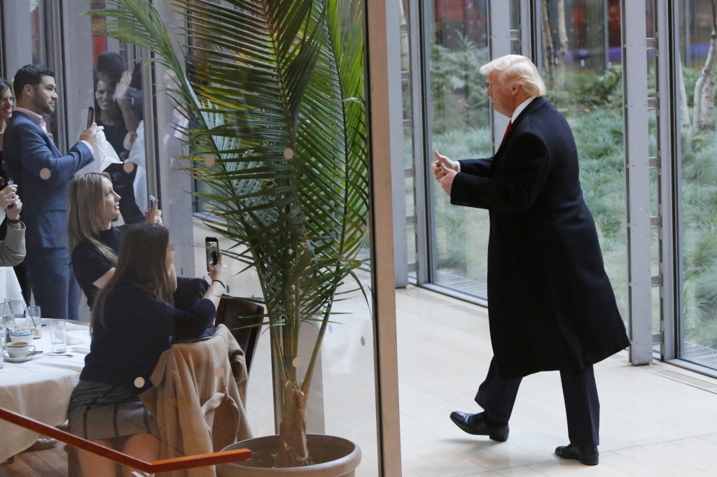 President-elect Donald Trump gestures to people seated in a restaurant as he leaves the New York Times building following a meeting Tuesday Nov. 22 2016 in New York