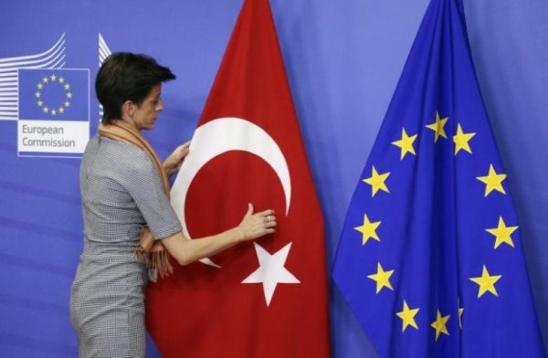 A woman adjusts the Turkish flag next to the European Union flag at the EU Commission headquarters in Brussels in this