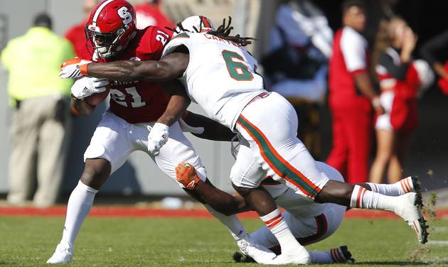 North Carolina State running back Matt Dayes is tackled by Miami's Shaquille Quarterman and Jamal Carter Sr. during the first half of an NCAA college football game at Carter Finley Stadium in Raleigh N.C. Saturday Nov. 19 2016. (Eth