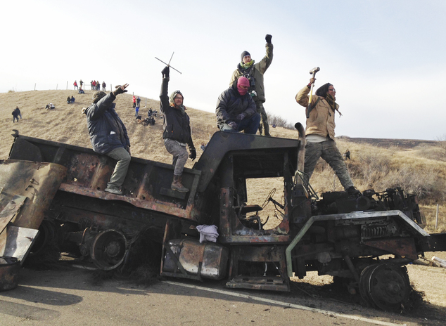 Protesters against the Dakota Access oil pipeline stand on a burned-out truck near Cannon Ball N.D. Monday Nov. 21 2016 that they removed from a long-cl