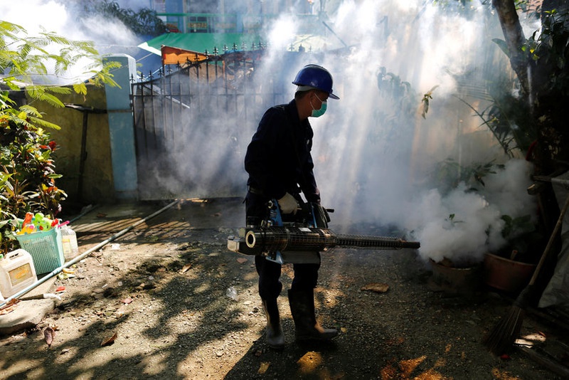 Worker fumigates along a street in Yangon Myanmar