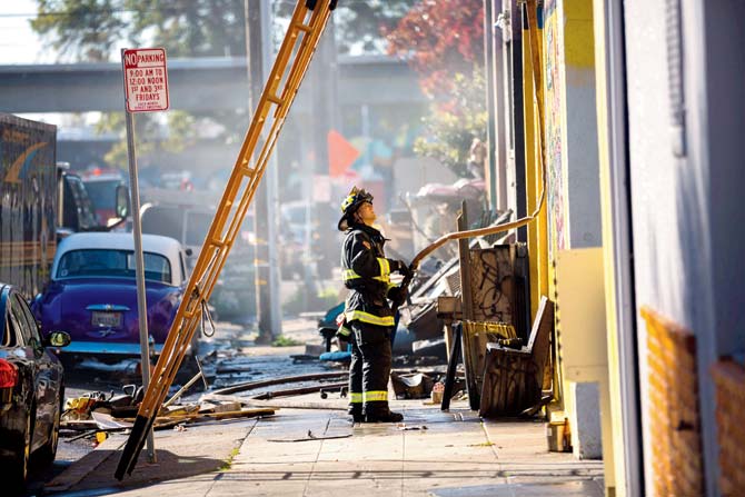 A fireman stands before a warehouse after it was destroyed by a fire in Oakland California. Pic  AFPOakland