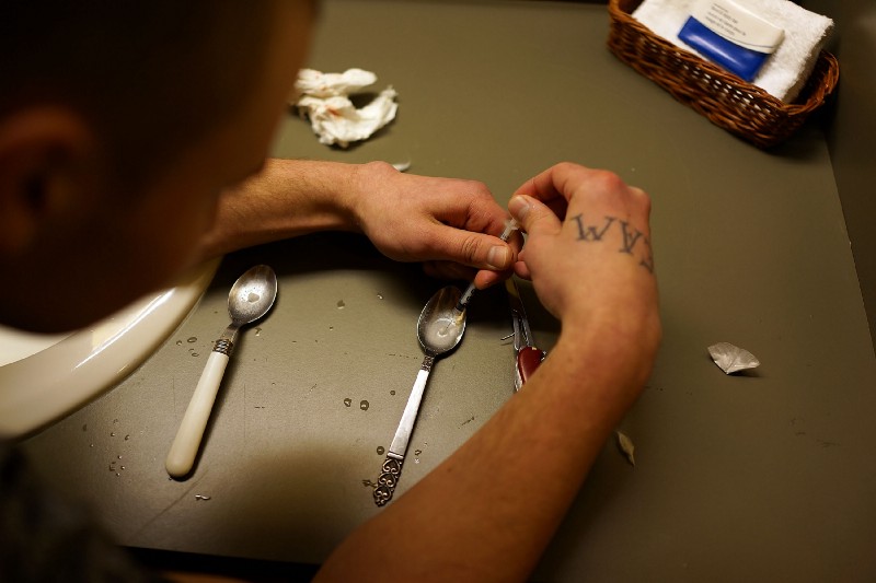 A heroin user prepares drugs to shoot intravenously