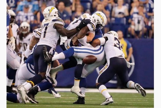 Indianapolis Colts Andrew Luck fumbles as he is hit by San Diego Chargers Jatavis Brown and Adrian Phillips during an NFL football game in Indianapolis