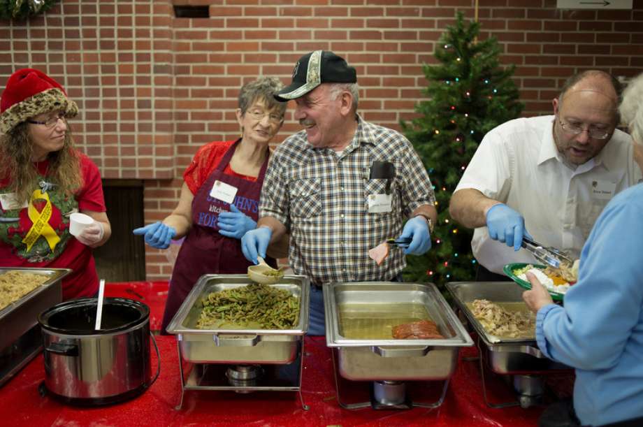 St. John's Lutheran Church members from left Judy Ruttan Elmer Thurston and Bruce Siebert dish out servings of gravy green beans and turkey during St. John's Lutheran Church's annual Christmas dinner in 2015