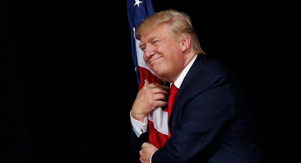 Donald Trump hugs a U.S. flag as he comes onstage to rally with supporters in Tampa Florida
