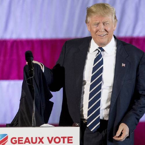 Trump takes off his coat while speaking at a rally in a DOW Chemical Hanger at Baton Rouge Metropolitan Airport Friday Dec. 9 2016 in Baton Rouge La