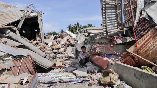 A boy sits on the rubble of a building that collapsed after an earthquake as he takes shelter from the sun in Pidie Jaya Aceh province Indonesia Wednesday