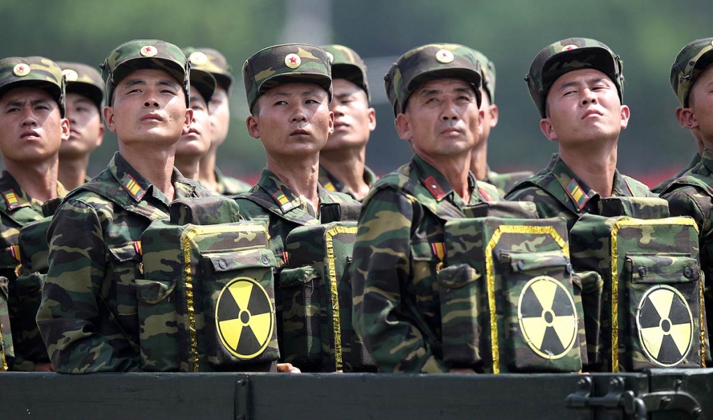 North Korean soldiers turn and look towards their leader Kim Jong Un from a military parade vehicle as they carry packs marked with the nuclear symbol during a ceremony marking the 60th anniversary of the Korean War armi