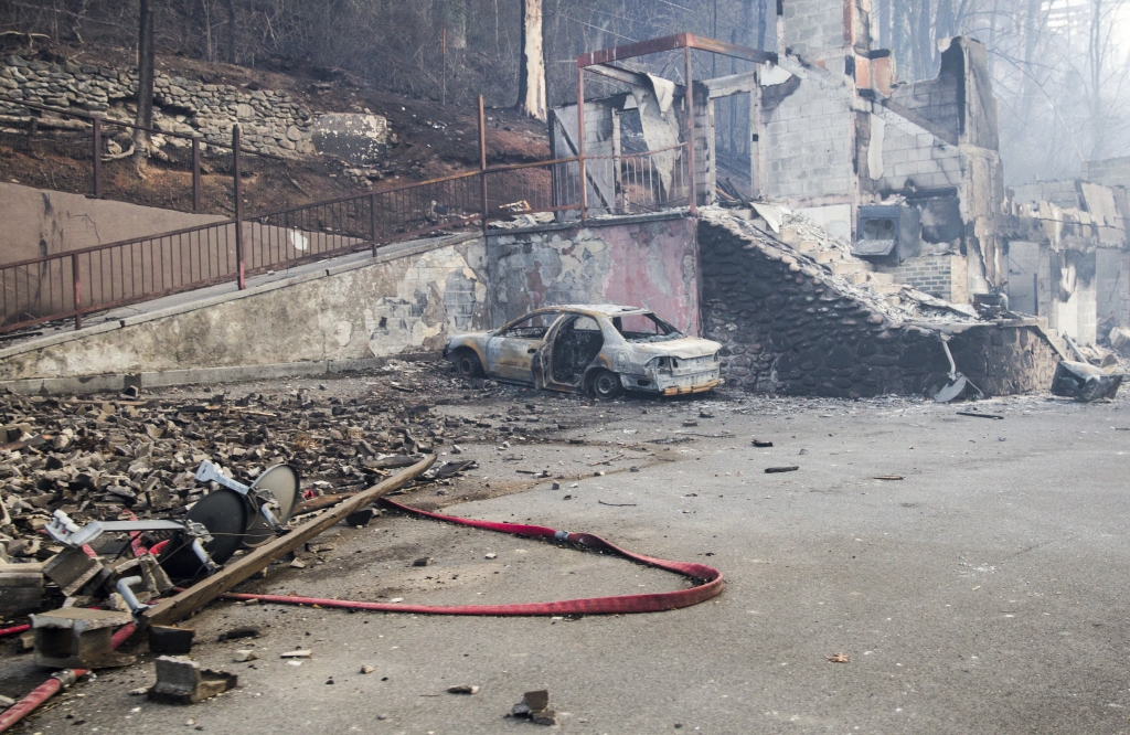 A scorched vehicle sits next to a burned out building in Gatlinburg Tenn. Tuesday Nov. 29 2016. The fatal fires swept over the tourist town the night before causing widespread damage. Thousands of people raced through a hell-like landscape to escape