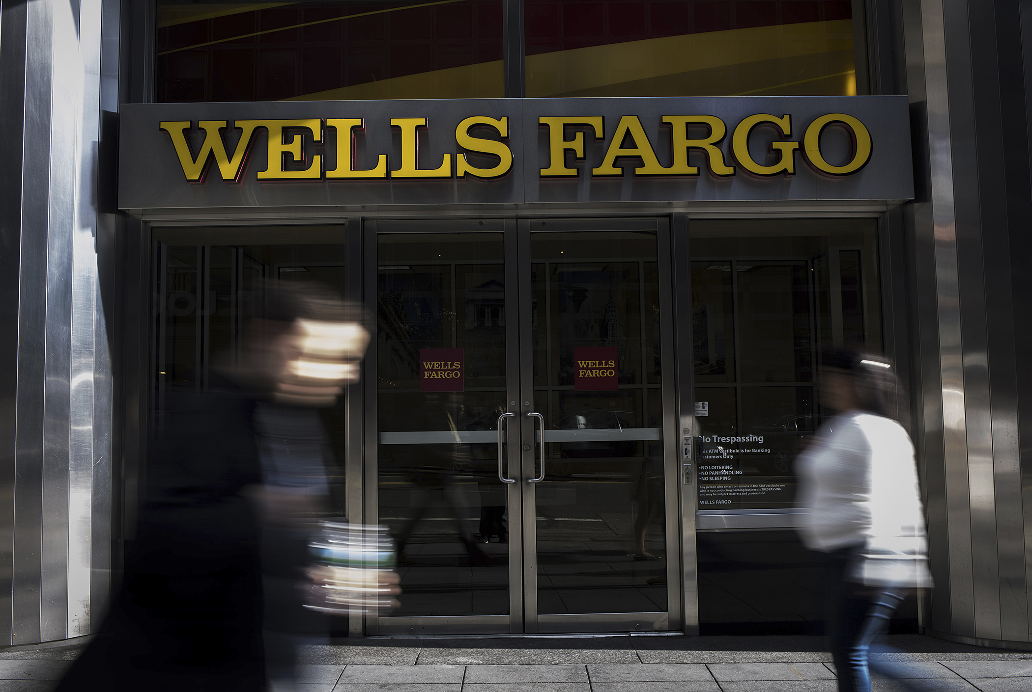 Pedestrians walk past Wells Fargo branch