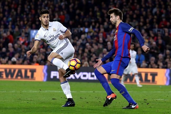 Real Madrid's Marco Asensio left goes for the ball with Barcelona's Gerard Pique during the Spanish La Liga soccer match between FC Barcelona and Real Madrid at the Camp Nou in Barcelona Spain Saturday Dec. 3 2016