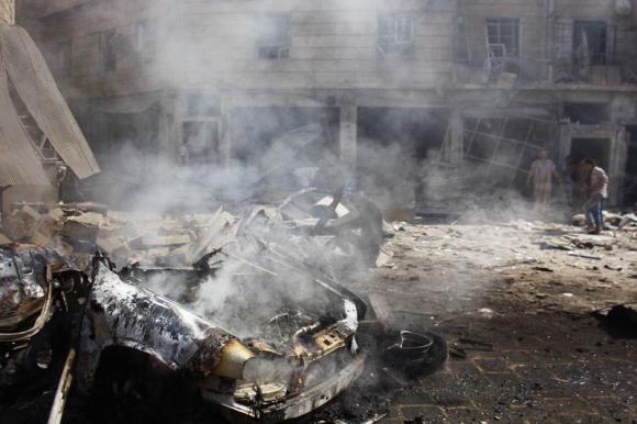 The wreckage of a burnt car is seen as people inspect a site hit by what activists said was a barrel bomb dropped by forces loyal to Syria's President Bashar al Assad at Qadi Askar district of Aleppo REUTERS  RAMI ZAYAT