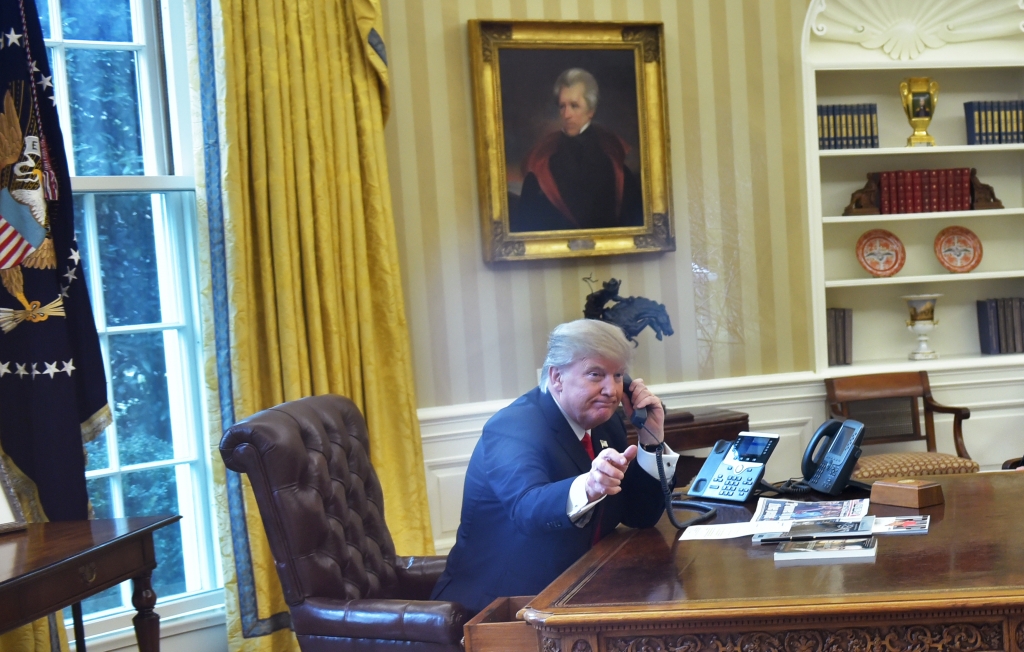 US President Donald Trump seen through an Oval Office window speaks on the phone to King Salman of Saudi Arabia in the Oval Office of the White House