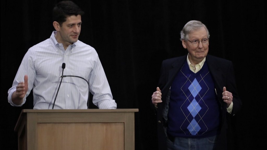 Senate Majority Leader Mitch Mc Connell opens his coat to show his sweater as House Speaker Paul Ryan speaks with members of the media during the GOP congressional retreat in Philadelphia