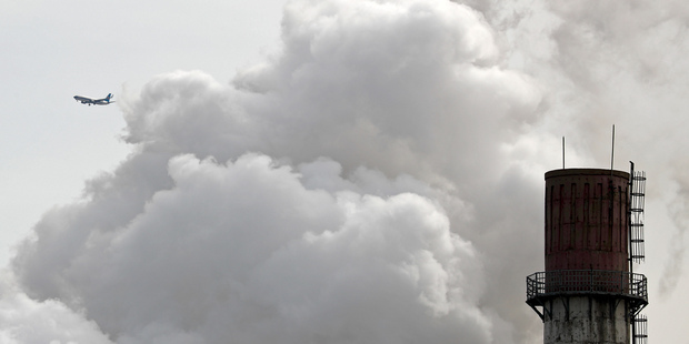 A passenger airliner flies past steam and white smoke emitted from a coal-fired power plant in Beijing China