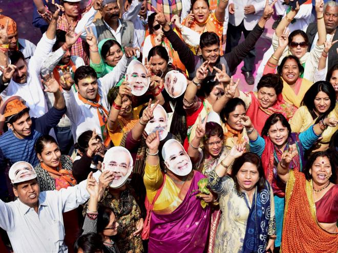 BJP workers and supporters wearing the mask of Prime Minister Narendra Modi celebrate the party's victory in the assembly elections at party headquarters in New Delhi on Saturday. PTI