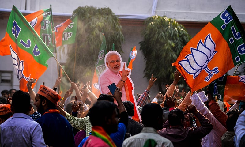 Supporters of BJP hold a cutout of Modi as they celebrate elections results.-AFP