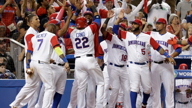 Dominican Republic's Robinson Cano is met by his teammates after scoring on a single by Carlos Santana during the sixth inning against the United States