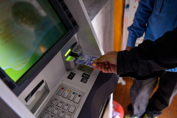 A man inserts his card to withdraw money from a mobile bank ATM machine in New