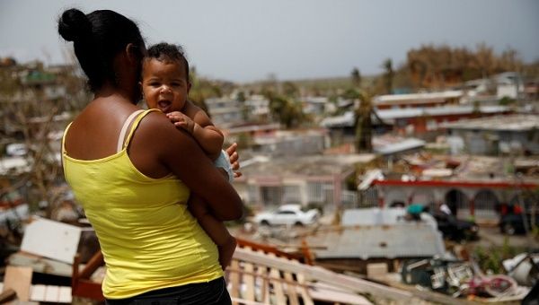 A woman carrying her son looks at the damage in the neighborhood after the area was hit by Hurricane Maria in Canovanas Puerto Rico