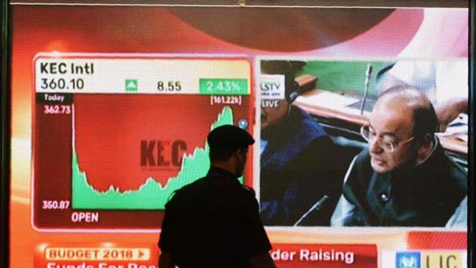 An Indian security guard walks past a digital screen showing Finance Minister Arun Jaitley delivering the budget speech. after four years in office we see that the government has been unable to come up with a sustainable formal job-creation initiative