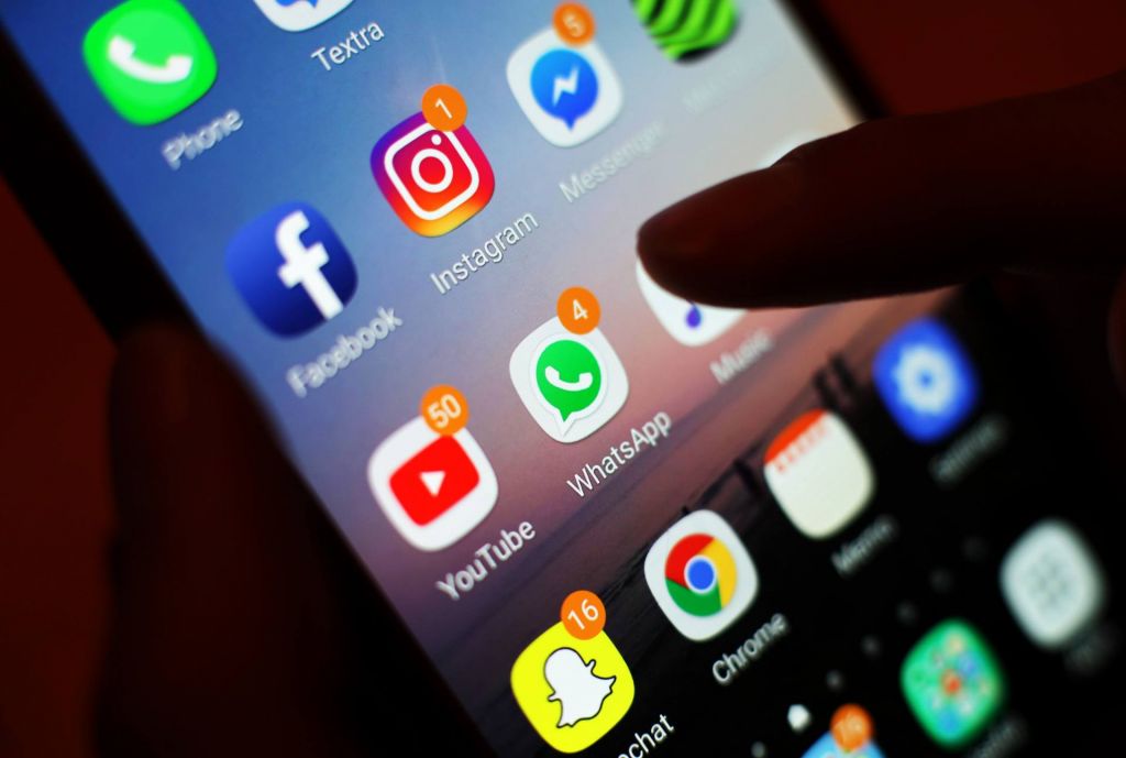 The icons of social media apps including Facebook Instagram You Tube and WhatsApp are displayed on a mobile phone screen
